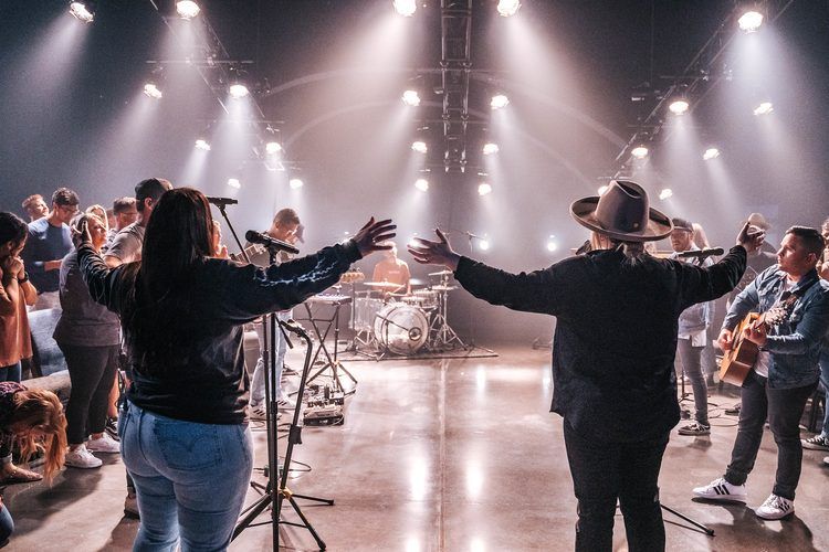 Musicians backlit with arms raised at the end of a set