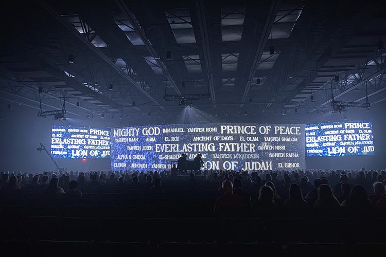Wide screen of type filling a darkened arena